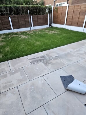 A patio area with a tiled floor and a grassy lawn.