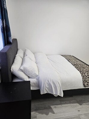 A bed with white bedding and a leopard print throw.