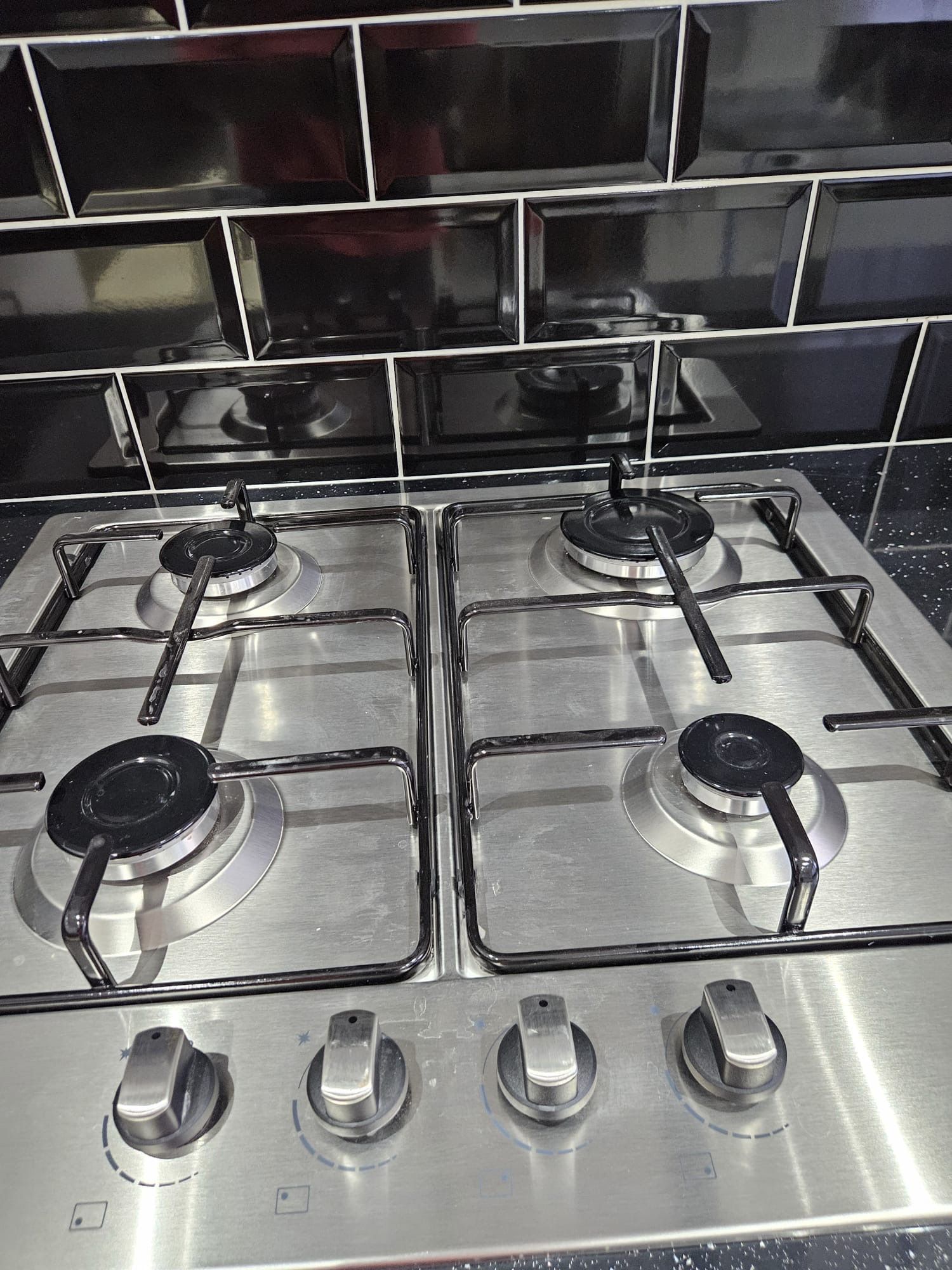 Une cuisine équipée de quatre brûleurs à gaz en acier inoxydable et de quatre boutons de réglage.