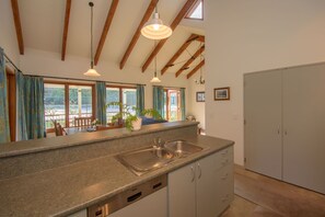 A kitchen with a Bosch dishwasher, a sink, and wooden beams on the ceiling. - Willowbrook Country Apartments (Speargrass Flat)