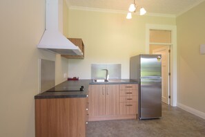 Eine Küche mit einem Edelstahl-Kühlschrank, Holzschränken, einer schwarzen Arbeitsplatte und einer weißen Dunstabzugshaube.