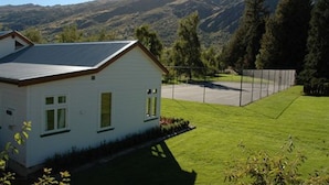 Una casa con techo inclinado, un jardín delantero y vistas a montañas al fondo.