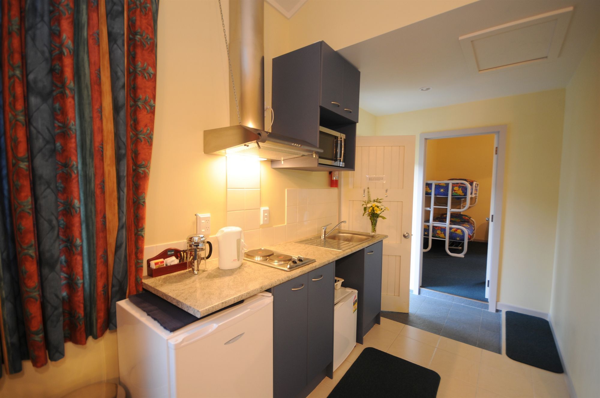 A compact kitchen with a microwave, coffee maker, and sink.