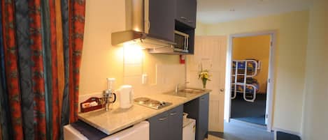 A compact kitchen with a microwave, coffee maker, and sink.