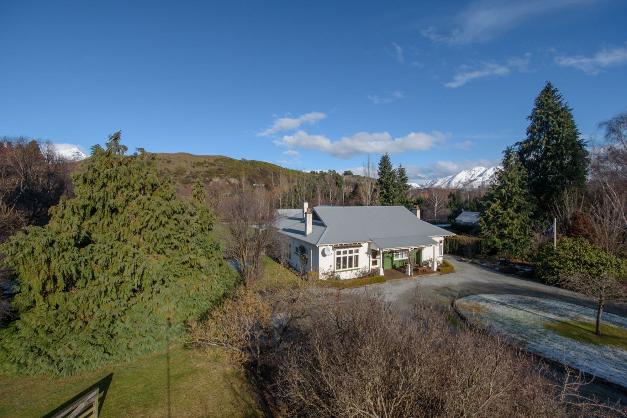 A house with a sloped roof, surrounded by trees and a mountain in the background.