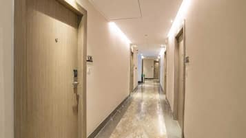 A hotel corridor with doors numbered 106 and 107, a marble floor, and a ceiling with recessed lighting.