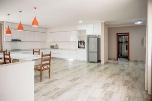 Eine moderne Küche mit weißen Schränken, einem Essbereich mit Holzstühlen und einem Kühlschrank.