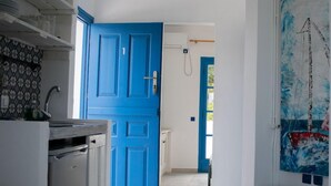 A kitchen with a blue door, a sink, and a countertop. - Aeraki Studios and Apartments (Naxos)