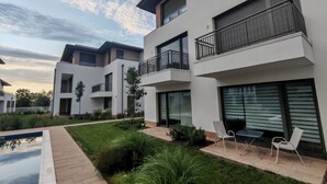 Un edificio residencial moderno con varios balcones, piscina y un jardín bien cuidado.