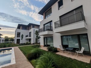 Un edificio residencial moderno con varios balcones, piscina y un jardín bien cuidado.
