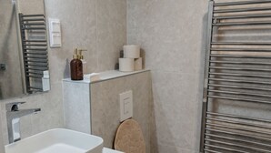 Un baño moderno con lavamanos, inodoro y toallero blancos.