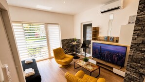 Una sala de estar moderna con un televisor de pantalla plana, sillones amarillos, una mesita de centro y una pared de acento de piedra.
