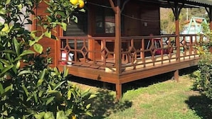 A wooden cabin with a porch and a covered area, surrounded by greenery. - Ikiz Villas (Kemer)