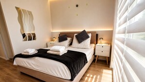 Ein modernes Schlafzimmer mit einem Bett, Nachttischen und einem wandmontierten Spiegel.