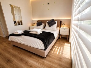 Un dormitorio moderno con cama, mesitas de noche y un espejo fijado a la pared.