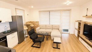 Eine moderne Küche mit Essbereich, einer Couch, einem Fernseher und einer Wand mit Steinakzenten.
