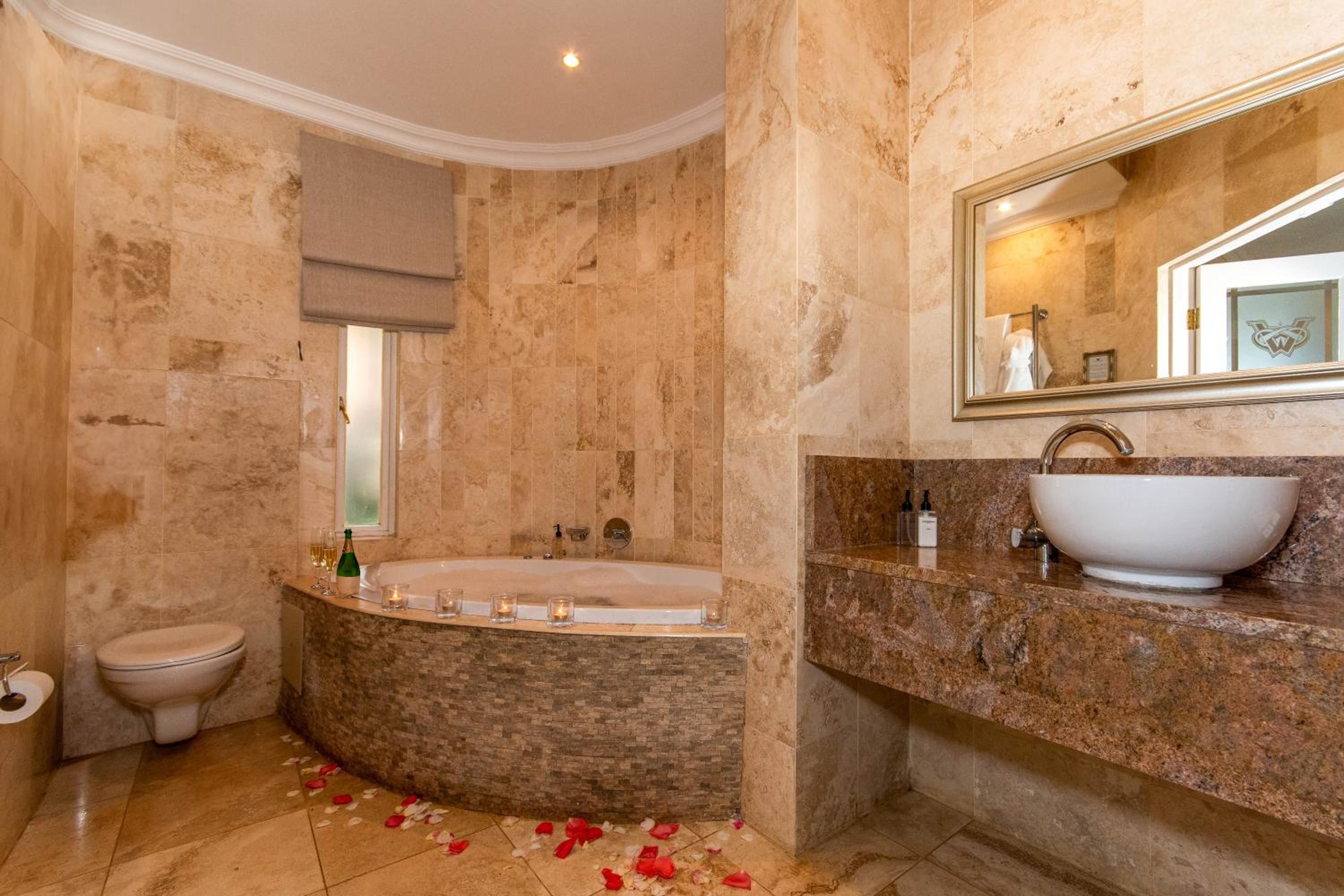 A bathroom with a bathtub, a toilet, and a large mirror.