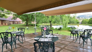 Un patio exterior con mesas y sillas, un estanque y una vista de un edificio al fondo.