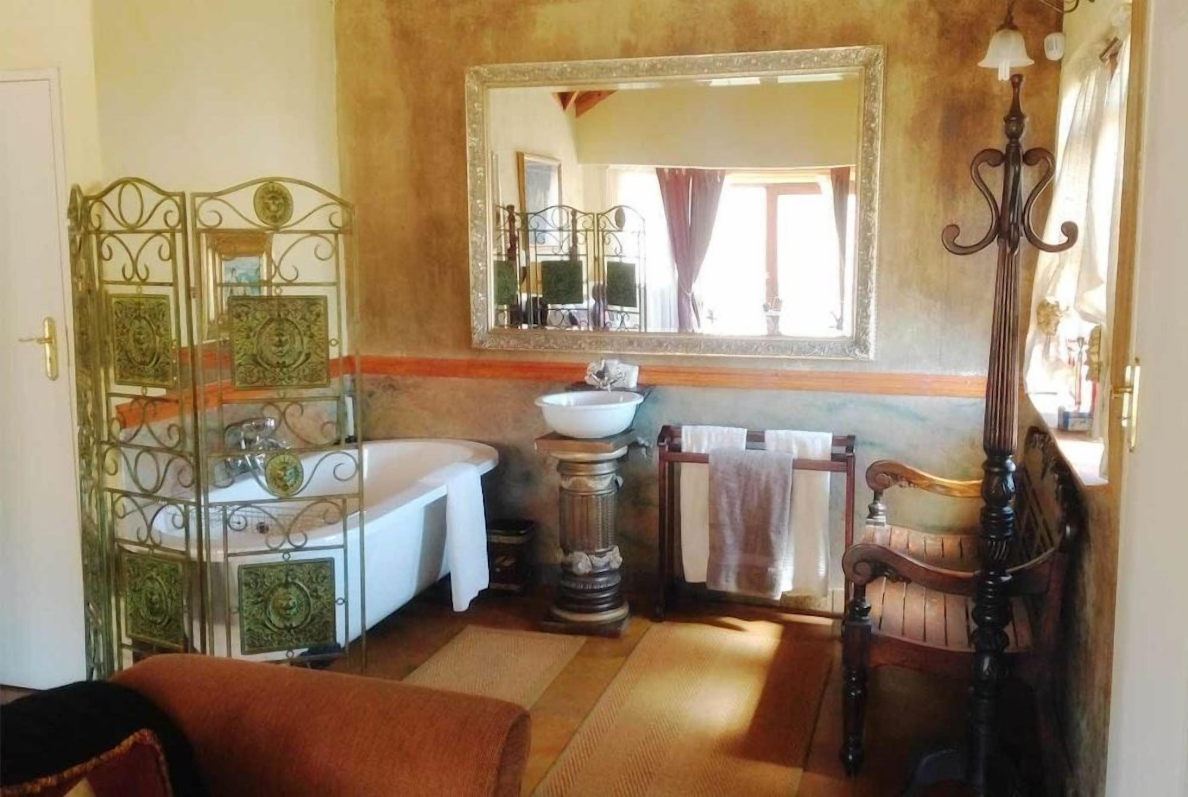 A bathroom with a bathtub, a sink, a mirror, and a decorative metal partition.