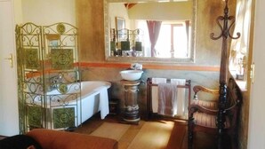 Casa de banho com banheira, pia, espelho e divisória metálica decorativa.