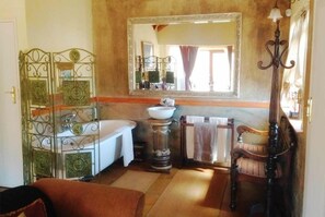 A bathroom with a bathtub, a sink, a mirror, and a decorative metal partition. - Fox and Squirrel (Dullstroom)