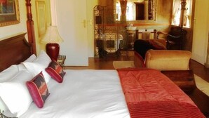 Quarto de hotel com uma cama, escrivaninha, cadeira e espelho.