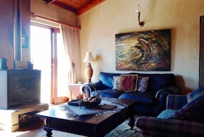 A cozy living room with a fireplace, a sofa, a coffee table, and a painting on the wall. - Fox and Squirrel (Dullstroom)