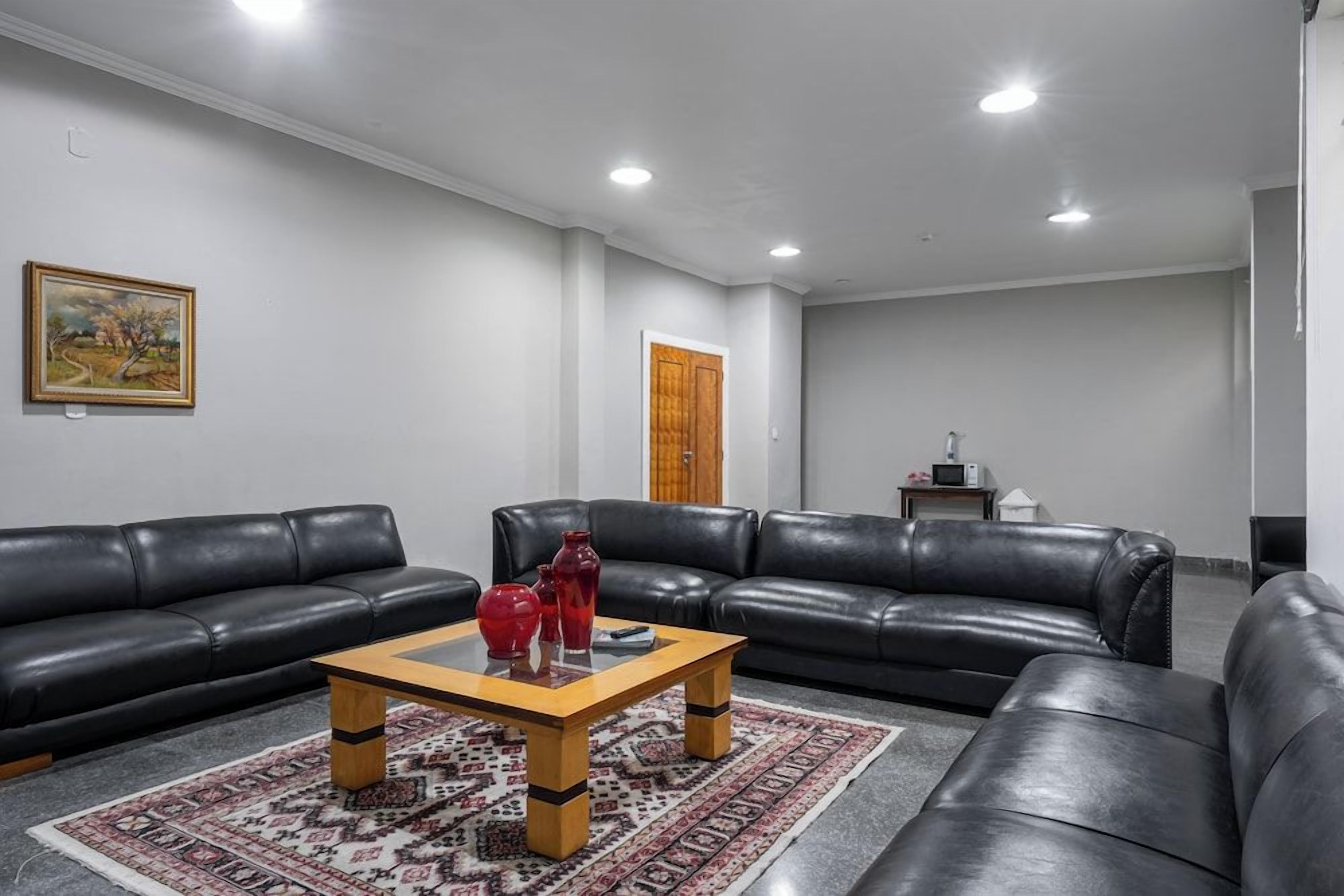 A living room with two black leather sofas, a wooden coffee table, and a patterned rug.