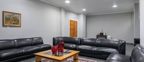 A living room with two black leather sofas, a wooden coffee table, and a patterned rug.