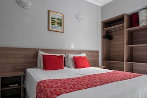 Quarto de hotel com cama, guarda-roupa e um quadro na parede.