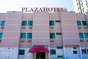 Um edifício com a placa 'PLAZAHOTEL' no topo.