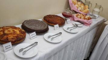 Mesa de buffet com diversos doces e um jarro de leite.