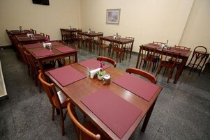 Un salón de conferencias con varias mesas y sillas de madera, dispuestas en filas.