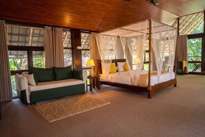 Un dormitorio con cama con dosel, un sofá y vistas al exterior.