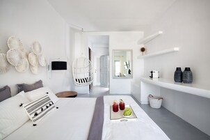 Un dormitorio moderno con cama, mesita de noche, sillón colgante y una barra desayunadora con objetos decorativos.