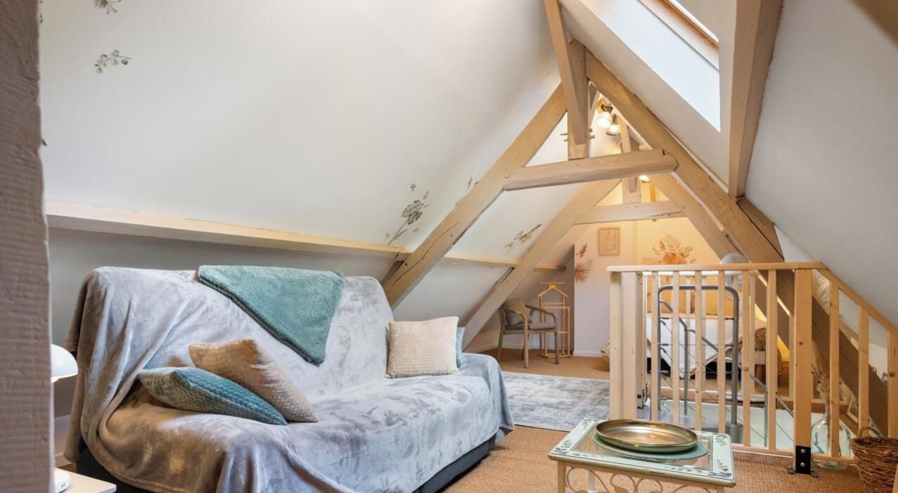 A cozy attic bedroom with a sloped ceiling, a wooden staircase, and a comfortable couch.