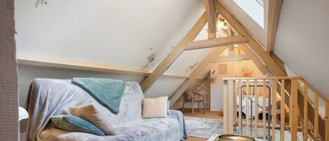 A cozy attic bedroom with a sloped ceiling, a wooden staircase, and a comfortable couch.