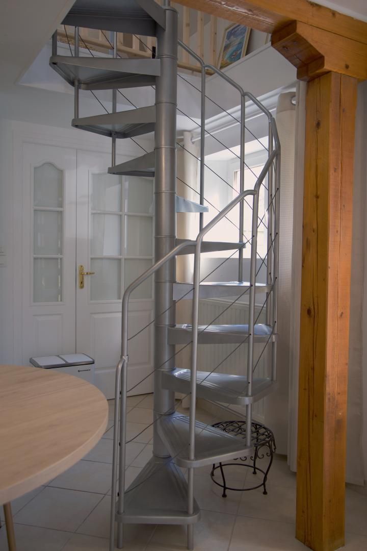 A spiral staircase with metal railings in a room with a white door and a round table.
