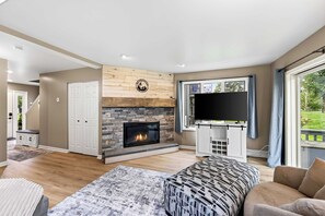 Ein modernes Wohnzimmer mit Kamin, Flachbildfernseher und großem Fenster.