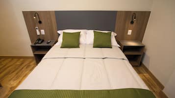 Habitación de hotel con una cama grande, dos mesitas de noche, un teléfono y una lámpara de pared.