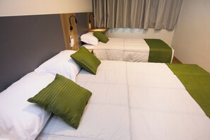 Une chambre d’hôtel avec deux lits, chacun étant équipé de draps blancs et d’oreillers verts.
