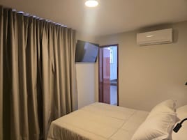 Quarto de hotel com cama, cortinas, ar condicionado e televisão.