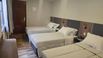 A hotel room with two beds, a desk, and a window with curtains.