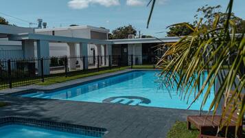 A swimming pool with a logo, surrounded by a fence, and a building with a number 10 sign.