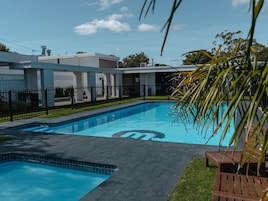A swimming pool with a logo, surrounded by a fence, with a building in the background.