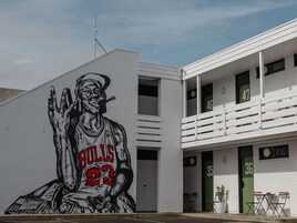A building with a mural of a basketball player, balconies, and doors numbered 35 and 36.