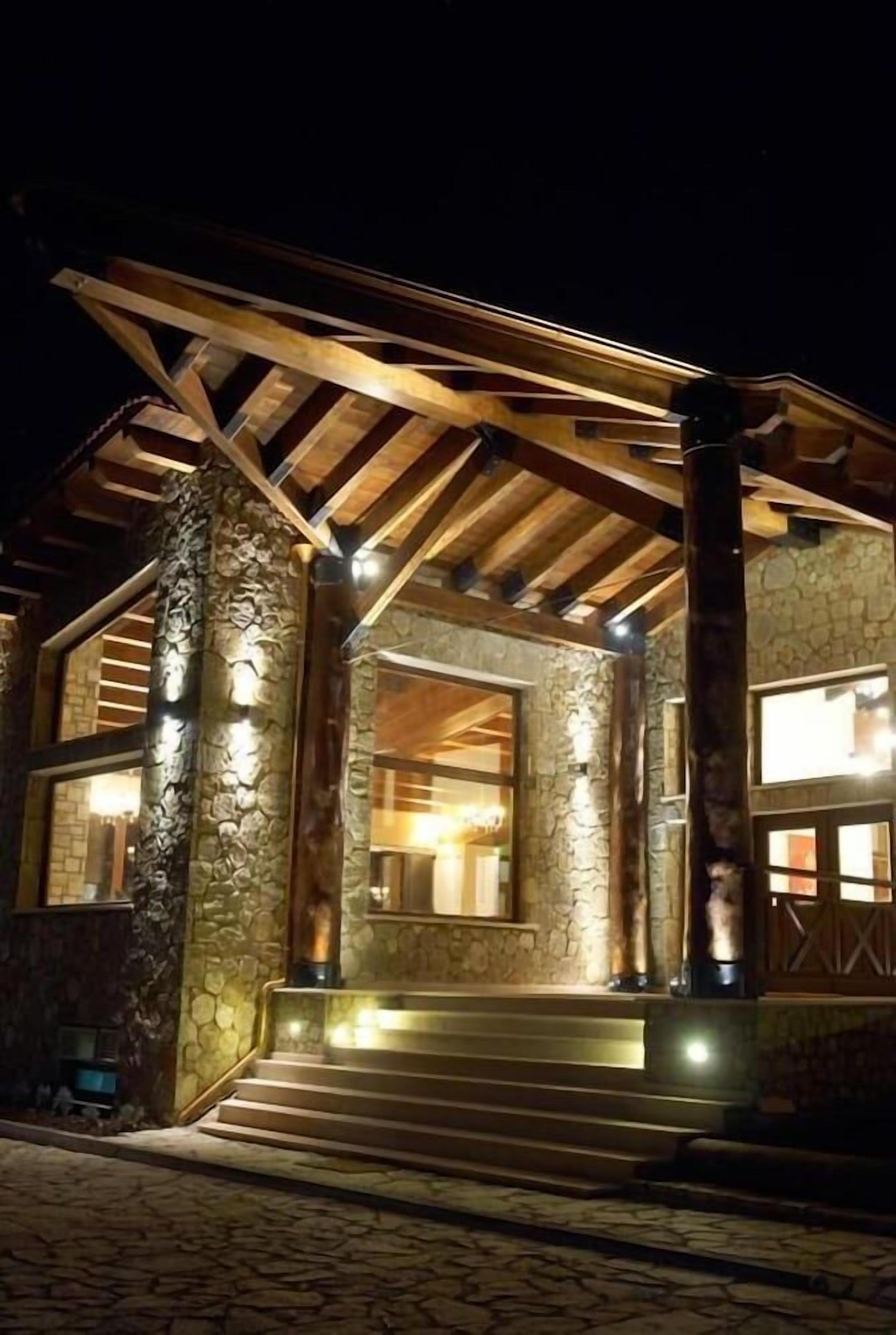 A stone building with a wooden facade, large windows, and a staircase leading to the entrance.