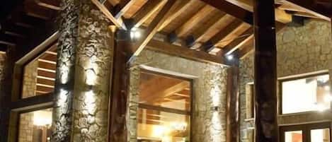 Un edificio de piedra con fachada de madera, ventanas amplias y una escalera que conduce a la entrada.