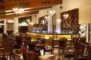 Interior de restaurant amb mobiliari de fusta, lampadaris i una zona de bar.