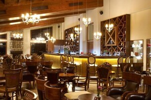 Interior de restaurante con muebles de madera, candelabros y una zona de bar.